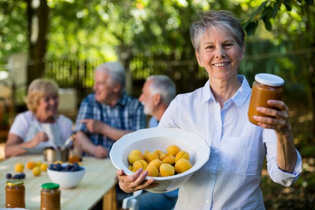 Ältere Frau, die Flasche Marmelade im Garten hält