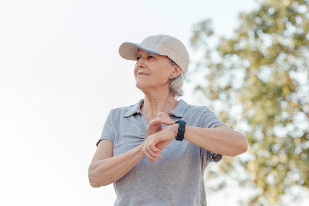 Ältere Frau, die ihre Sportuhr im Freien timt