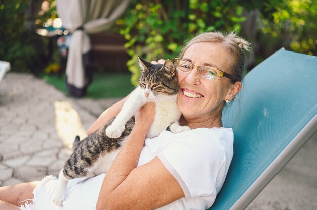 Ältere Frau, die im Garten mit einer Katze entspannt