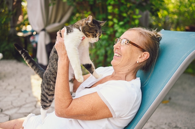 Ältere Frau, die im Garten mit einer Katze entspannt