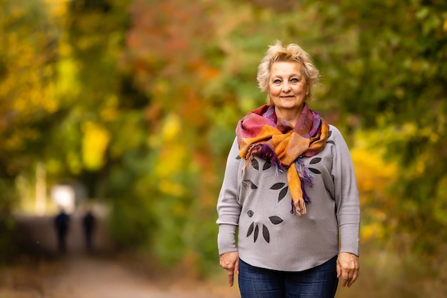 Ältere Frau, die im Herbst im Park spazieren geht