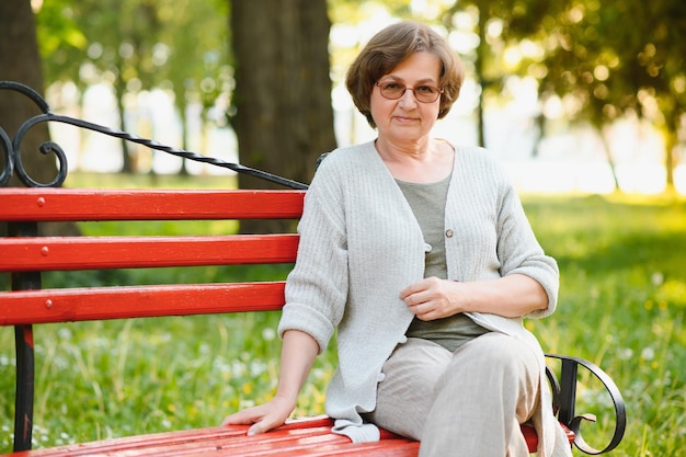 Ältere Frau, die im Sommer im Park spazieren geht