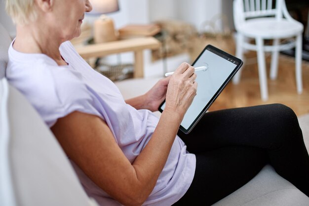 Ältere Frau, die in einer Yogahaltung vor einem offenen Laptop sitzt