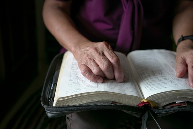 Ältere Frau, die mit den Händen auf einem offenen Buch liest