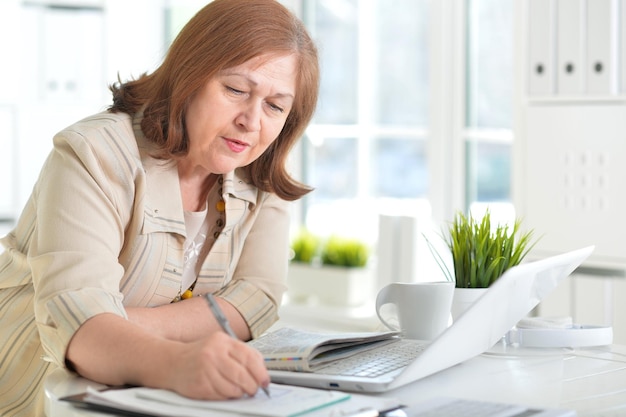 Ältere Frau, die mit Laptop arbeitet