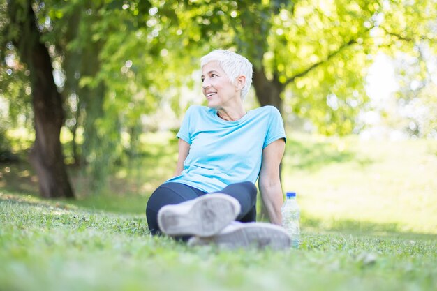 Ältere Frau, die nach dem Training im Park sitzt und sich ausruht