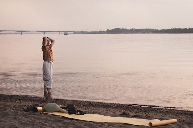 Ältere Frau, die nach Yoga am Flussufer steht