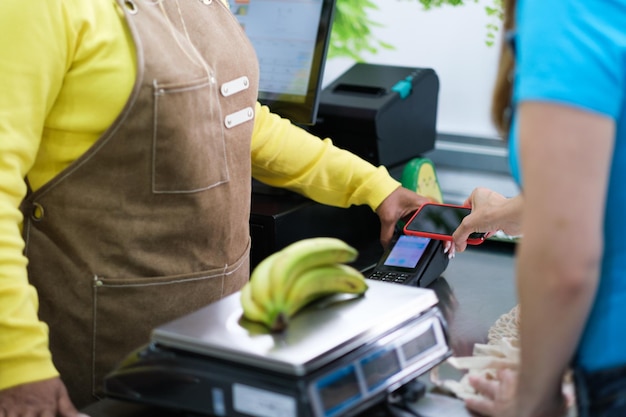 Ältere Frau, die Obst verkauft und über Handy auflädt