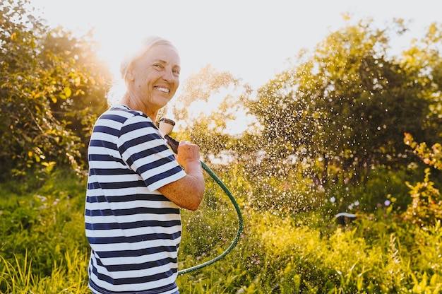 Ältere Frau, die Pflanzen im Garten wässert