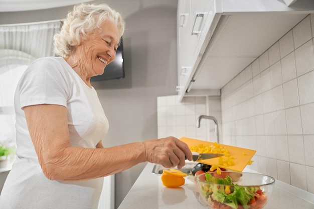 Ältere Frau, die Salat in der Küche macht