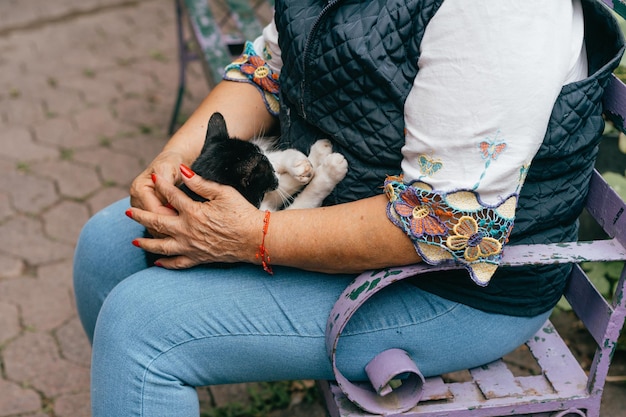 Ältere Frau, die sich im Sommergarten im Freien entspannt und Hauskatze umarmt Konzept für alte Rentner und Haustiere