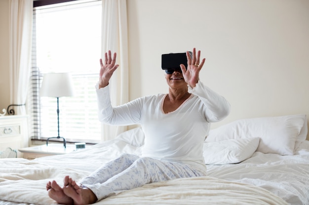 Ältere Frau, die virtuelles Headset auf Bett verwendet