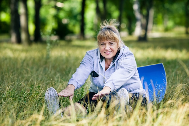 Ältere Frau, die Yoga im Park tut