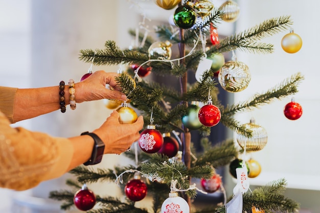 Ältere Frau, die zu Hause einen Weihnachtsbaum schmückt