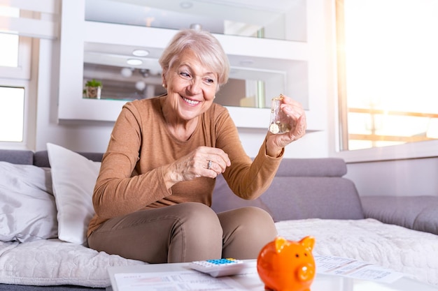 Ältere Frau, die zu Hause Finanzen macht, glückliche ältere Frau mit Rechner und das Zählen von Euro-Geld zu Hause Geschäftssparungen Rentenversicherung Alter und Menschenkonzept