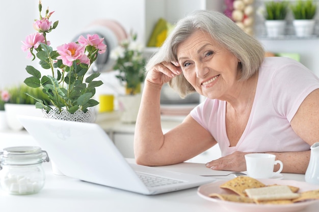 Ältere Frau, die zu Hause mit Laptop arbeitet