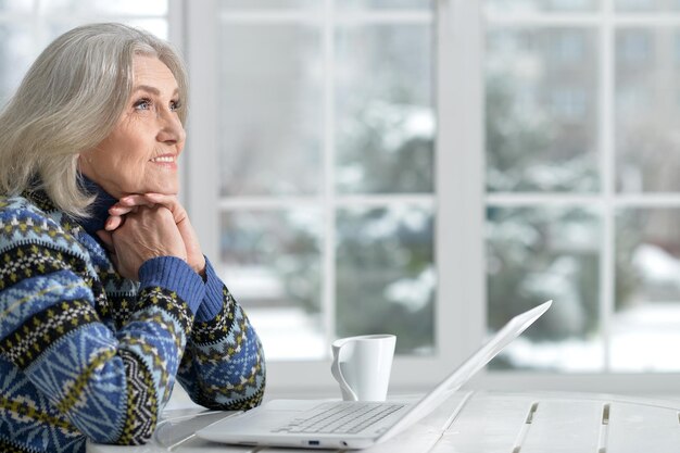 Ältere Frau, die zu Hause mit Laptop arbeitet