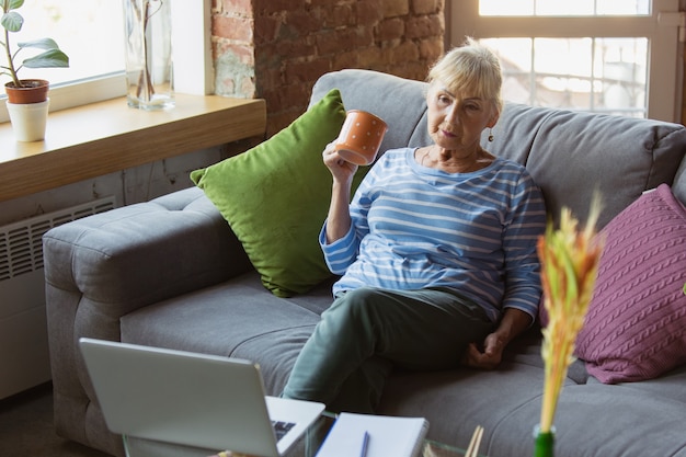 Ältere Frau, die zu Hause studiert und Online-Kurse erhält