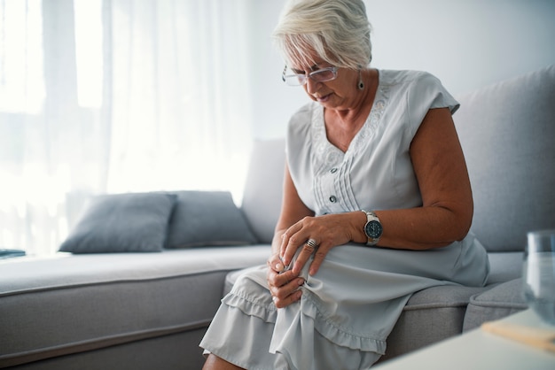 Ältere Frau, die zu Hause unter den Schmerz im Knie leidet