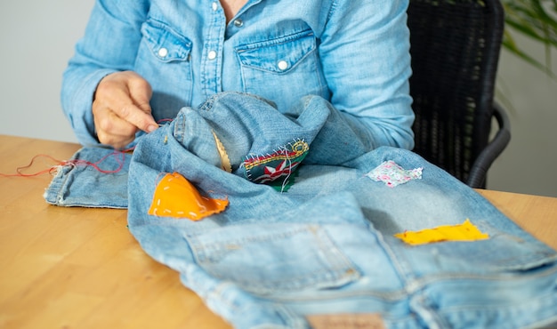 Ältere Frau Hände nähen auf einem Stoff Jeans