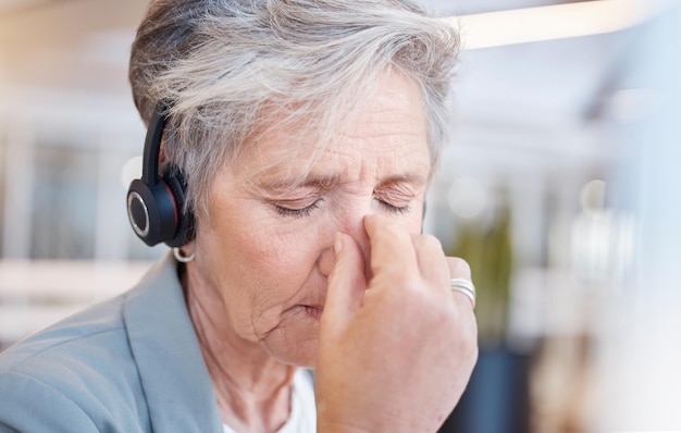 Ältere Frau im Callcenter mit Kopfschmerzen und Müdigkeit wegen Stress durch Telemarketing-Beratung oder CRM-Job. Ältere technische Supportberaterin und erschöpft im Büro mit Burnout-Müdigkeit oder Angstzuständen