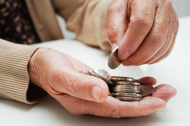 Ältere Frau im Ruhestand, die Münzengeld zählt und sich um die monatlichen Ausgaben und die Zahlung der Behandlungsgebühr sorgt