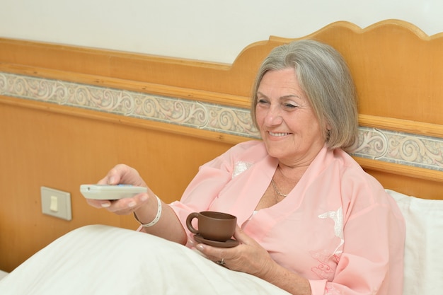 Ältere Frau im Schlafzimmer mit Tasse Kaffee