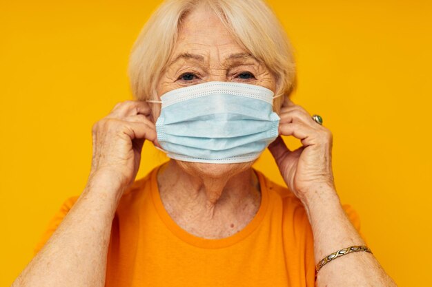 Ältere Frau in gelben T-Shirts in medizinischer Maske, beschnittene Ansicht