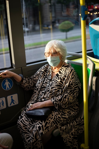 Ältere Frau in öffentlichen Verkehrsmitteln mit Gesichtsmaske