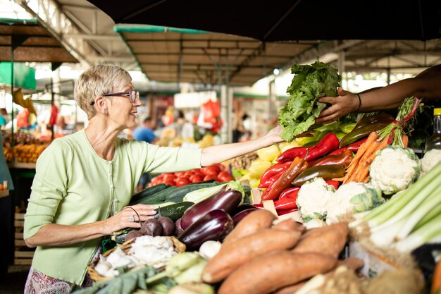 Ältere Frau kauft frisches Bio-Gemüse auf dem Marktplatz für gesunde Ernährung.