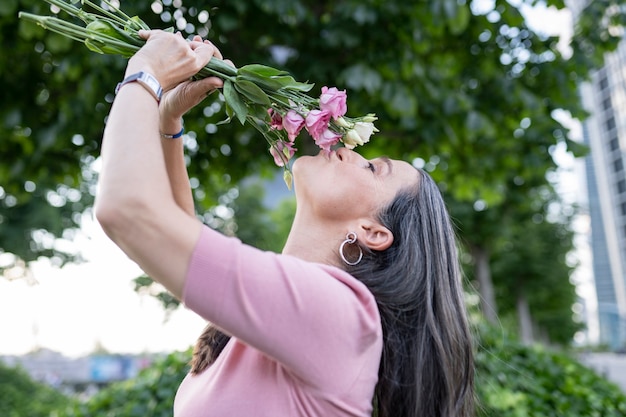 Ältere Frau mit Blumen im Park