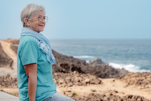 Ältere Frau mit Brille, die am Strand sitzt und entspannende Momente genießt