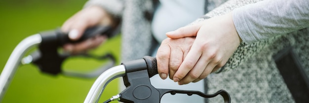 Ältere Frau mit Gehhilfe beim Spaziergang im Park eines modernen Pflegeheims