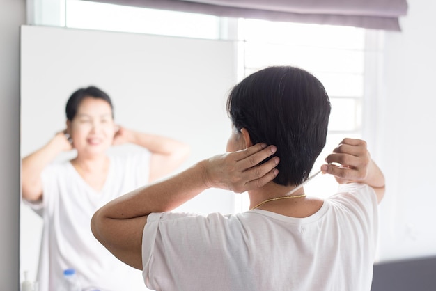 Ältere Frau mit Kamm mit Haaren vor SpiegelRückansicht