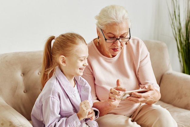 Ältere Frau mit kleinem Mädchen, das Smartphone verwendet