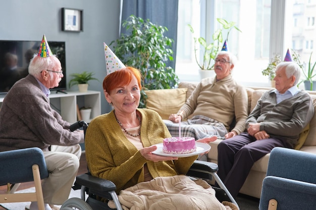 Ältere Frau mit Kuchen, die ihren Geburtstag feiert