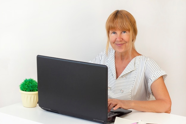 Ältere Frau mit Laptop. Geschäftsfrau, die an einem Laptop im Büro arbeitet