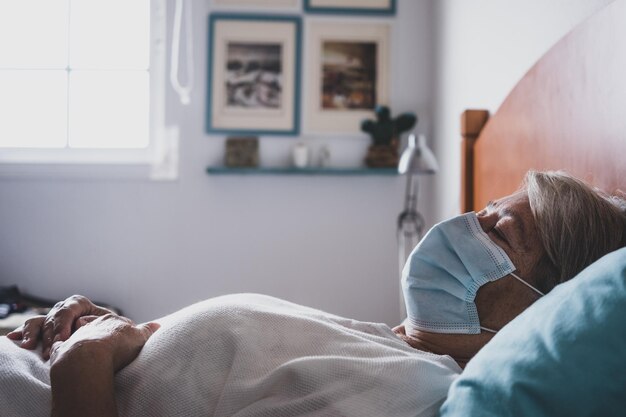 Ältere Frau mit Maske schläft zu Hause im Bett