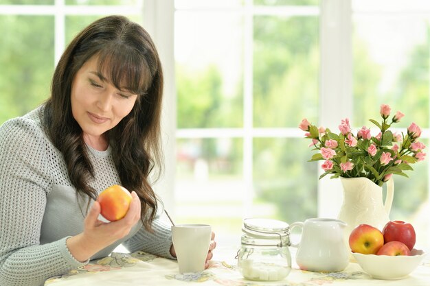 Ältere Frau mit Obst und Tee zu Hause