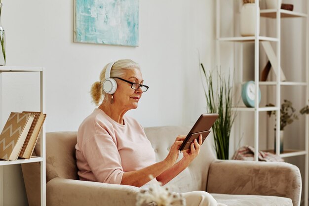 Ältere Frau mit Tablet zu Hause