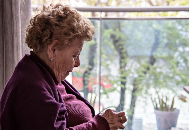 Ältere Frau sitzt am Fenster und näht.