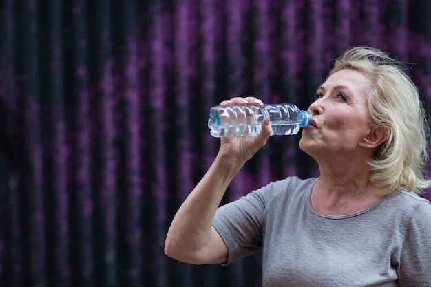 Ältere Frau trinkt Wasser in Flaschen nach dem Training