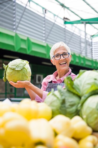 Ältere Frau verkauft Gemüse auf dem Markt