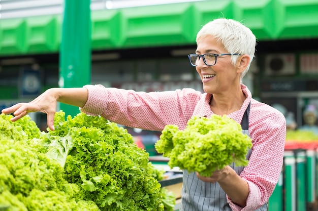 Ältere Frau verkauft Kopfsalat auf Markt