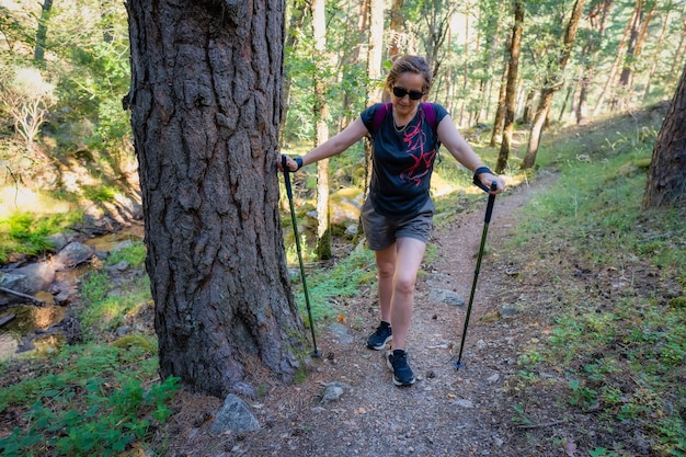 Ältere Frau wandert auf einem steilen Pfad in einem Wald in Guadarrama Madrid