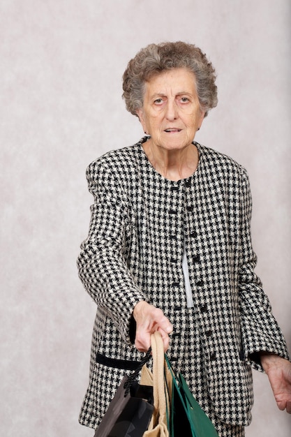 Ältere Frau zwischen 70 und 80 Jahren behält Einkaufstüten