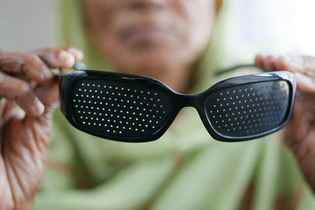 Ältere Frauen, die eine Perforationsbrille mit Löchern zum Trainieren des Sehvermögens halten