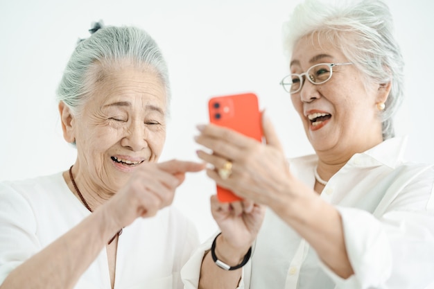 Ältere Frauen, die mit einem Lächeln auf Smartphone-Bildschirme schauen