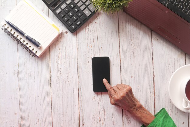 Ältere Frauen übergeben unter Verwendung des Smartphones auf Tisch.