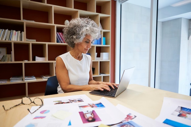 Ältere Geschäftsfrau, die am Laptop im Büro arbeitet